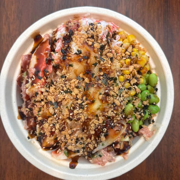 Overhead view of a Yo Poké Fusion bowl with crab, corn, edamame, and crispy toppings.